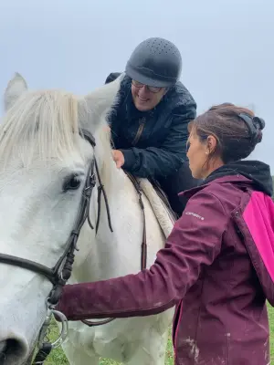 Jeune fille en situation de handicap à dos de cheval avec monitrice spécialisée qui tient les rênes du cheval durant un atelier d'équi-handi à l'association les enfants extraordinaires à Barjac.
