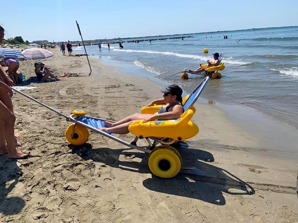 Jeune fille dans un fauteuil roulant de plage en bord de plage. Sortie vacances les enfants extraordinaires Barjac.